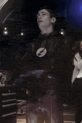 a man in a flash costume is standing next to a woman in a white shirt .