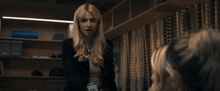 a woman in a black jacket is talking to another woman in a room