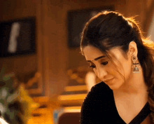 a woman wearing a black top and earrings looks down