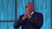 a man in a suit and tie is clapping in front of a steve harvey logo