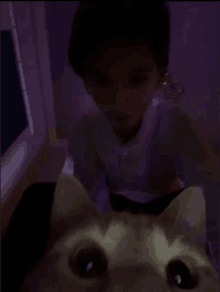 a young boy is playing with a cat in the dark