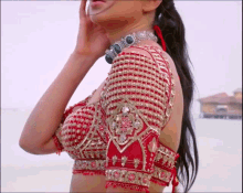 a woman wearing a red and gold blouse and a silver necklace
