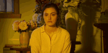 a woman sits in front of a vase of flowers