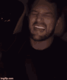 a man with a beard is smiling and holding a cell phone in his hand