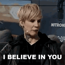 a woman in a leather jacket is talking into a microphone and saying i believe in you