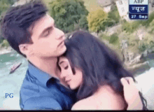 a man is hugging a woman in front of a sign that says abp 27 sep