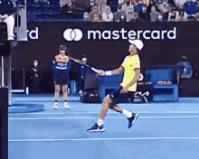 a man is holding a tennis racquet in front of a mastercard ad