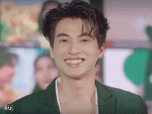 a young man in a green suit is smiling .