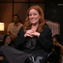 a woman in a tuxedo is sitting in a chair with her legs crossed and a # porc logo in the corner