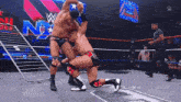 two wrestlers are fighting in a ring with a w logo on the wall behind them