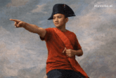 a man in a red shirt and a black hat is pointing at something