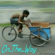 a man is riding a bicycle with a cart attached to it on a road .