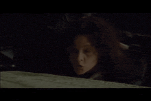 a woman in a dark room with her mouth open looks at the camera