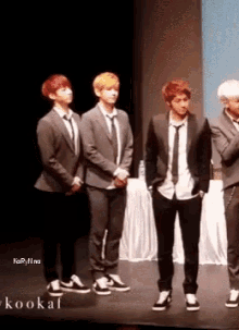 a group of young men in suits and ties are standing on a stage with the word kookai in the lower right corner
