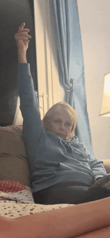 a woman sitting on a couch with her arm up in the air