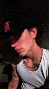 a man wearing a hat and a white tank top has a tattoo on his arm that says ' i love you '