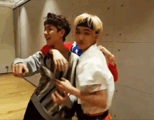 two young men are hugging each other in a room . one of the men is wearing a headband .