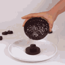 a person is holding a chocolate ball on a plate