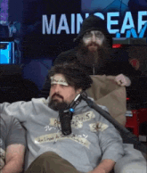 a man with a beard is sitting in front of a microphone in front of a sign that says main ear