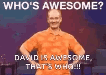 a man in an orange shirt is standing on a stage .