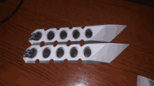 a pair of knives on a wooden surface with holes in them