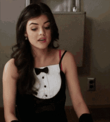 a woman wearing a tuxedo and gloves is sitting in front of a wall .