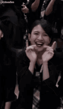 a woman is laughing and waving her hands in the air in front of a crowd .