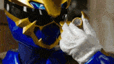 a blue and gold superhero is holding a watch