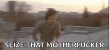 a blurry picture of a man running on a roof with the words `` seize that motherfucker '' behind him .