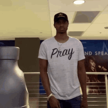 a man wearing a pray shirt stands in front of a bottle