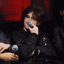 a man holding a microphone with the word adidas on his jacket