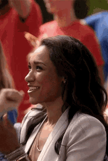 a woman is smiling in front of a crowd of people .