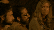 a group of people are sitting in a dark room with a cbs logo in the corner .