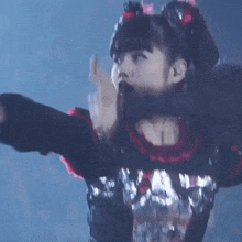 a woman in a black and red dress is dancing on a stage in front of a crowd .