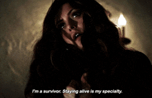 a woman says " i 'm a survivor staying alive is my specialty " in a dark room