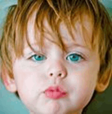 a close up of a child 's face with blue eyes and red hair .