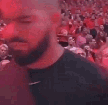 a man with a beard is standing in front of a crowd in a stadium .