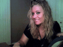 a woman with blonde hair and a black shirt is smiling