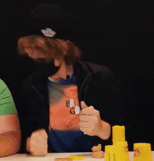 a man wearing a mask is sitting at a table with a group of people .