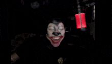 a person with a mickey mouse face painted on their face is standing in front of a microphone .