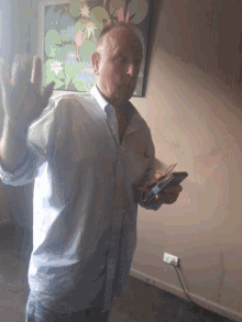 a man in a blue shirt is holding a cell phone in his hand