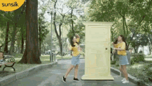 two girls are standing in front of a yellow sunsilk sign