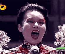 a woman with blood on her face is singing into a microphone on a stage .