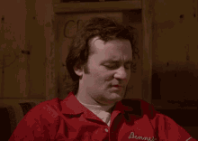 a man wearing a red shirt that says dennis