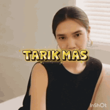a woman sitting on a bed with tarik mas written on her face