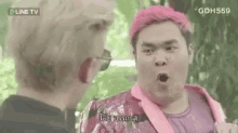 a man with pink hair is talking to another man in a pink jacket .