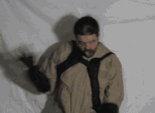 a man wearing a tan jacket and black gloves