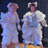 a girl with pink hair is dancing with another girl in a white outfit