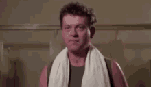 a man with a towel around his neck is standing in a bathroom .