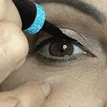 a close up of a woman applying eyeliner to her eye